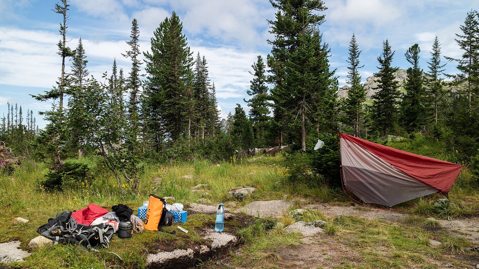 Dome tents pitched at a mountain campsite with camping gear laid out in front of them