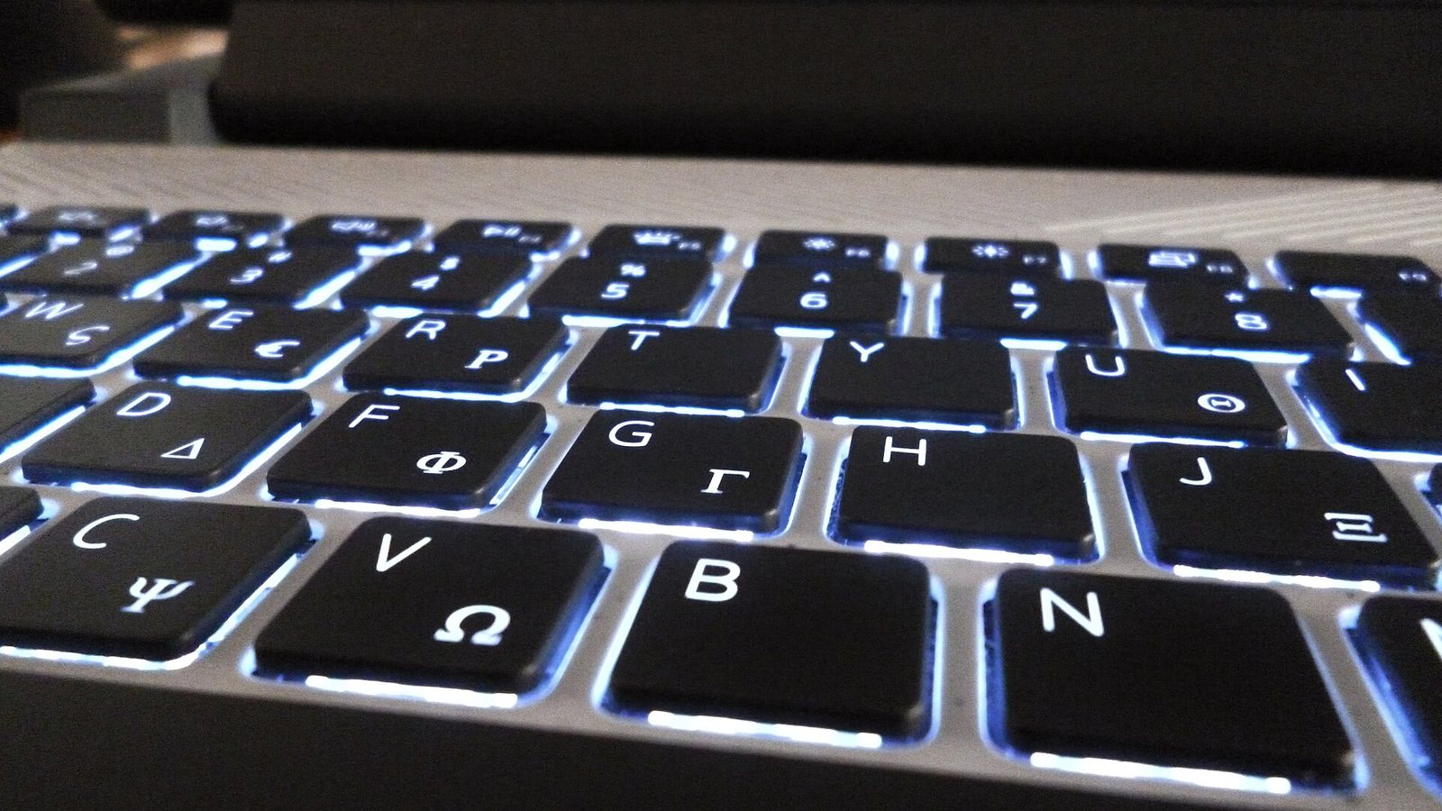 A backlit laptop keyboard glowing in a dim room