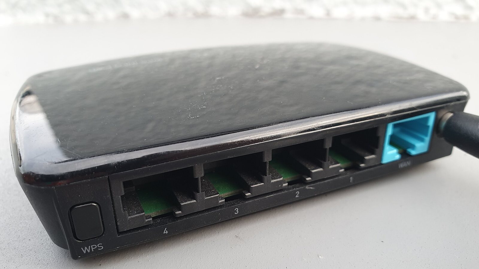 A black Wi-Fi router seen from the back, with its Ethernet ports