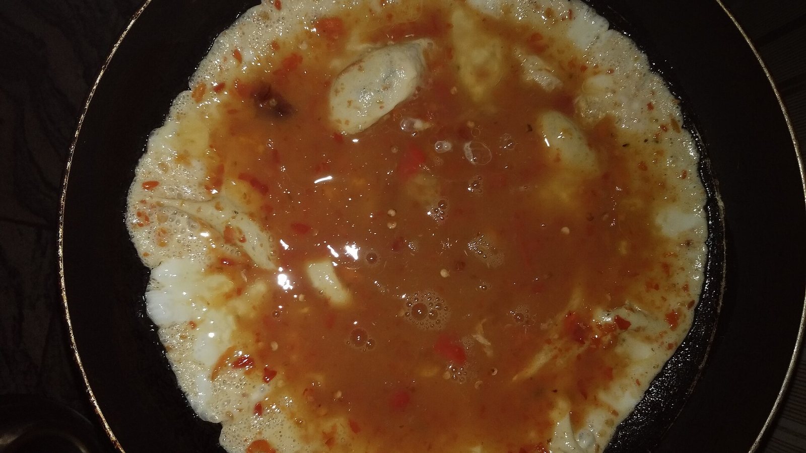An egg frying in a dark nonstick pan
